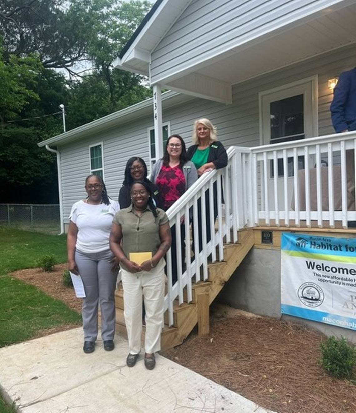 New homeowners smile for a photo at a home dedication by the Macon Area Habitat for Humanity on Thursday.