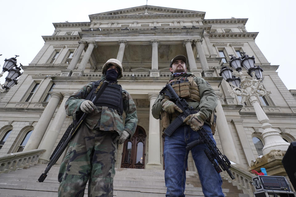 FILE - In this Jan. 6, 2021, file photo, armed men stand on the steps at the State Capitol after a rally in support of President Donald Trump in Lansing, Mich. In the past year, insurrectionists have breached the U.S. Capitol and protesters have forced their way into statehouses around the country. But the question of whether guns should be allowed in capitol buildings remains political and states are going in opposite directions. (AP Photo/Paul Sancya, File)