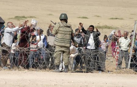 A Turkish soldier stands guard as Syrian Kurds wait behind the border fence to cross into Turkey near the southeastern town of Suruc in Sanliurfa province, September 19, 2014. REUTERS/Stringer