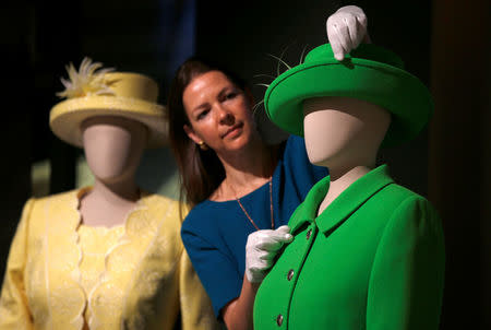 Curator Caroline de Guitar, poses for photographers next to Britain's Queen Elizabeth's green ensemble worn for Trooping the Colour in 2016 marking her official 90th birthday, ahead of the opening of an exhibition entitled 'Fashioning a Reign: 90 Years of Style from the Queen's Wardrobe', at Buckingham Palace, in London, Britain July 21, 2016. REUTERS/Peter Nicholls