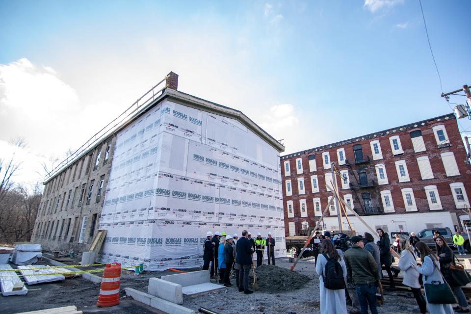 Politicians gather on Jan. 3 to throw ceremonial dirt in front of one of three mill buildings being converted into the income-restricted Millrace apartments in Woonsocket.