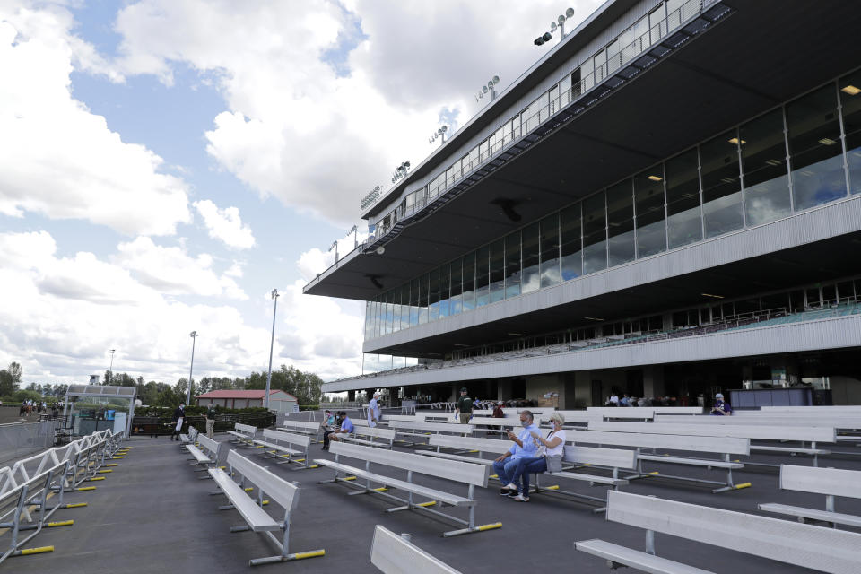 Stands are empty except for owners and grooms Wednesday, June 24, 2020, before a horse race at Emerald Downs Racetrack in Auburn, Wash., on the first day of racing at the track since all professional sports in Washington state were curtailed in March by the outbreak of the coronavirus. No spectators were allowed, but online wagering was available and the races were streamed. Organizers hope to continue racing into October on a modified schedule. (AP Photo/Ted S. Warren)