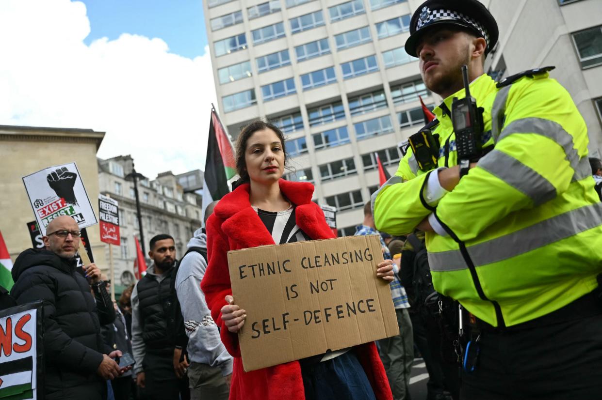 A woman holds a placard saying ‘ethinic cleansing is not self defence' (AFP via Getty Images)