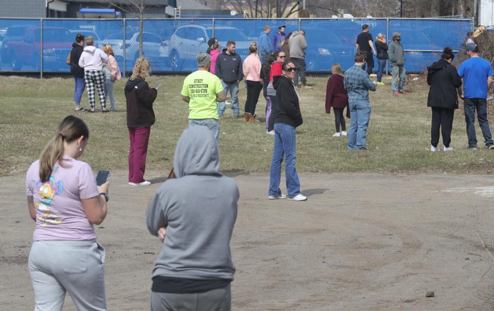 Parents anxiously wait outside a fenced area at Coventry High School on Tuesday while authorities investigate and apparent hoax call claiming a man had shot people inside the school.