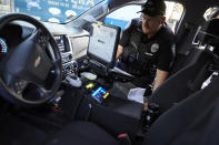 Gresham Police Sgt. Travis Garrison runs an ID and insurance check in Gresham, Ore., Thursday, July 21, 2022. Gresham, a Portland suburb, has seen an increase in fatal shootings and gun violence at the same time as it has a shortage of officers. To address the situation, the department has shut down all of its specialized units except for its mental health unit and shifted all of its detectives to work homicides. (AP Photo/Craig Mitchelldyer)