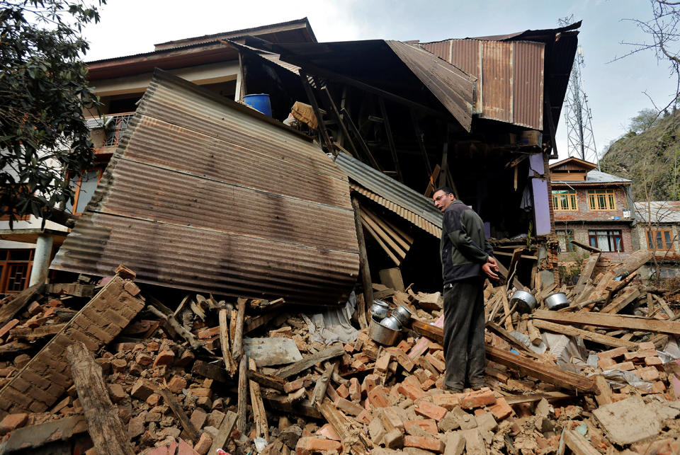 A man stands amidst the rubble of a house which was damaged by incessant rains in Srinagar