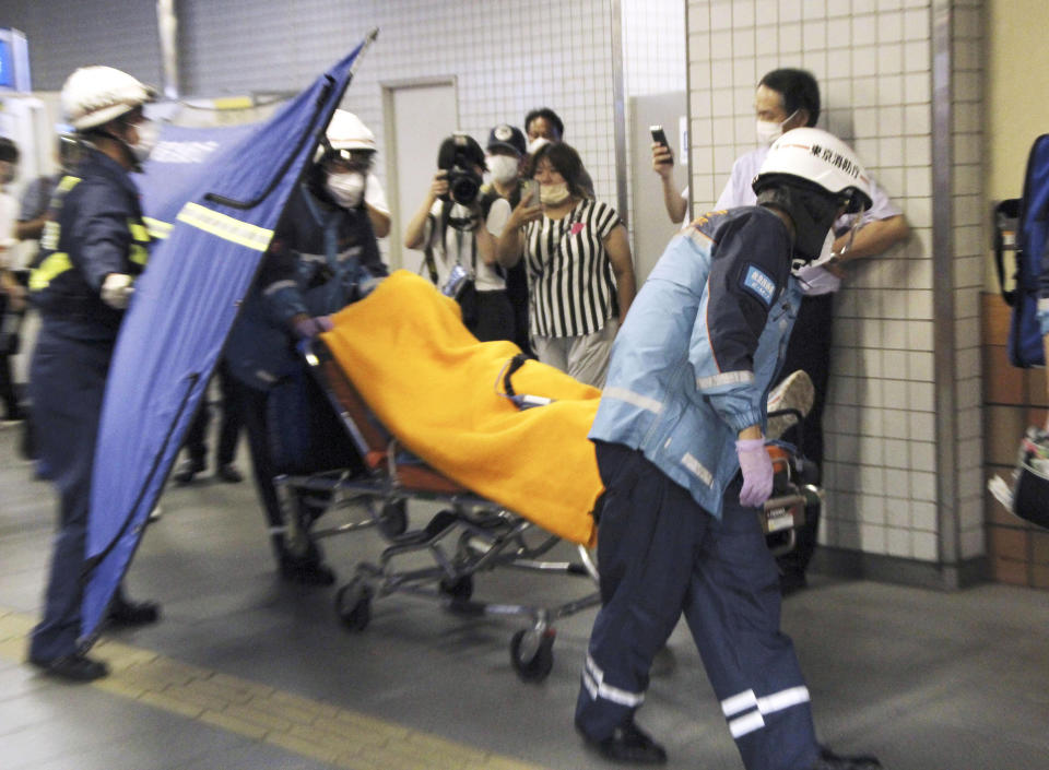 Rescuers carry an injured passenger on stretcher at Soshigaya Okura Station after stabbing on a commuter train, in Tokyo Friday night, Aug. 6, 2021. A man with a knife attacked 10 passengers on a commuter train in Tokyo on Friday and was arrested by police after fleeing, fire department officials and news reports said. (Kyodo News via AP)