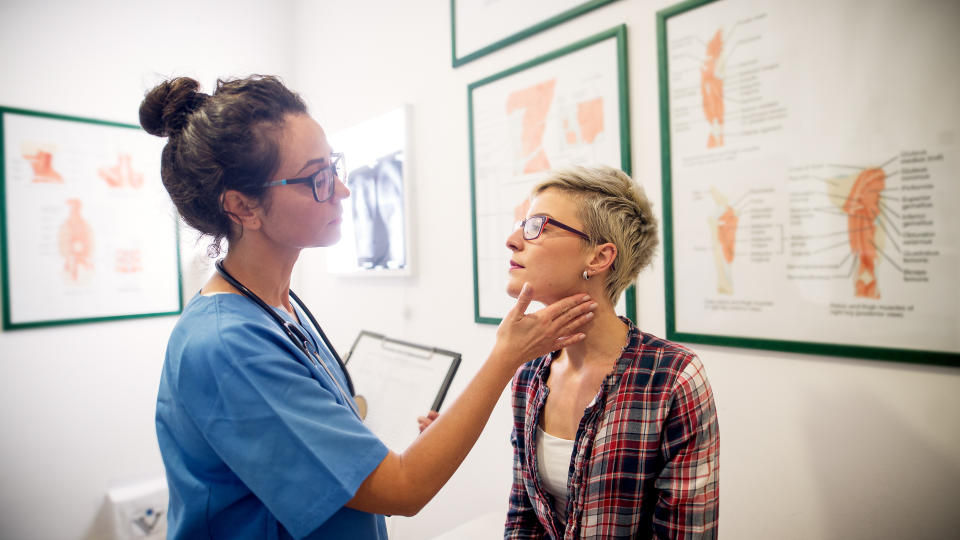 Professional beautiful medical doctor examining patient in her office.