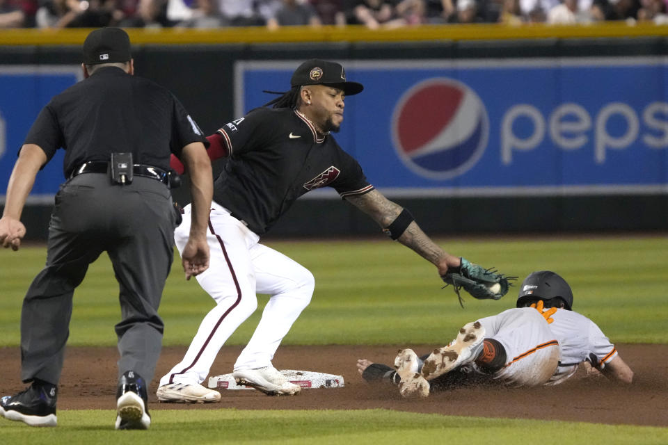 San Francisco Giants' Casey Schmitt, right, is tagged out trying to steal second base by Arizona Diamondbacks second baseman Ketel Marte, center, in the fifth inning during a baseball game, Saturday, May 13, 2023, in Phoenix. (AP Photo/Rick Scuteri)