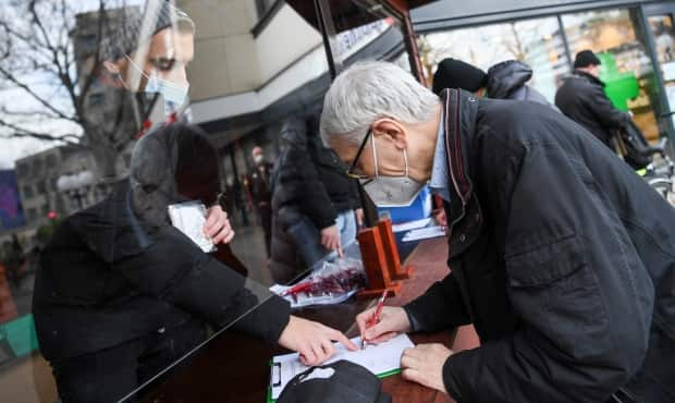 A man signs for an allocation of FFP2 masks from a pharmacy in Germany. A number of European jurisdictions, including the German state of Bavaria, Austria, and the Czech Republic, have mandated the use of N95-style masks in public. 