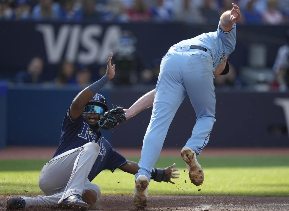 Tampa Bay Rays' Junior Caminero, left, slides ahead of a tag by Toronto Blue Jays starting pitcher Wes Parsons, right, during second-inning baseball game action in Toronto, Sunday, Oct. 1, 2023. (Frank Gunn/The Canadian Press via AP)