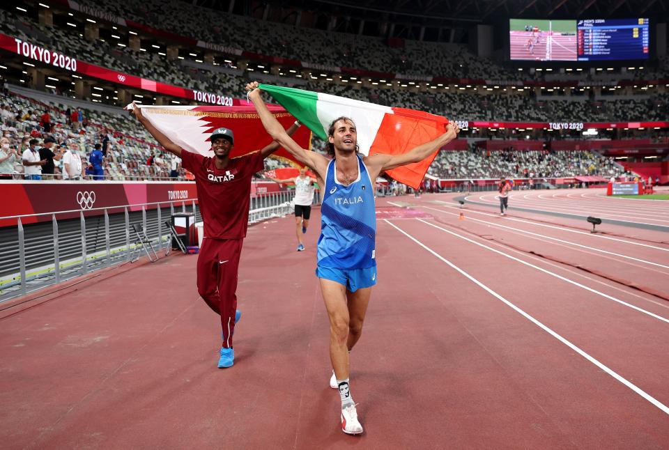 Gold medallists Mutaz Essa Barshim (left) of Qatar and Gianmarco Tamberi of Italy celebrate on the track following the men's high jump final at the 2020 Tokyo Olympics. 