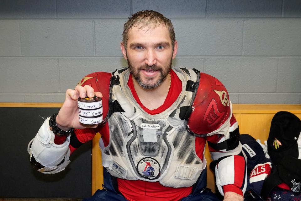 Washington Capitals' Alex Ovechkin holds his 798, 799, and 800th career goal pucks in the locker room after an NHL hockey game against the Chicago Blackhawks Tuesday, Dec. 13, 2022, in Chicago. (AP Photo/Charles Rex Arbogast)