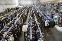 In this photo taken Wednesday, April 9, 2014, marketing manager Kate Systrom pulls a designer blouse from a rack at the headquarters of The RealReal in San Francisco. An explosion of resale online sites from RealReal to Chairish that allows shoppers to easily trade in their gently used top brand handbags, furniture and gadgets for cash is changing the way Americans buy. The ease of reselling their possessions allows consumers to keep refreshing their wardrobes and homes without feeling guilty. (AP Photo/Eric Risberg)