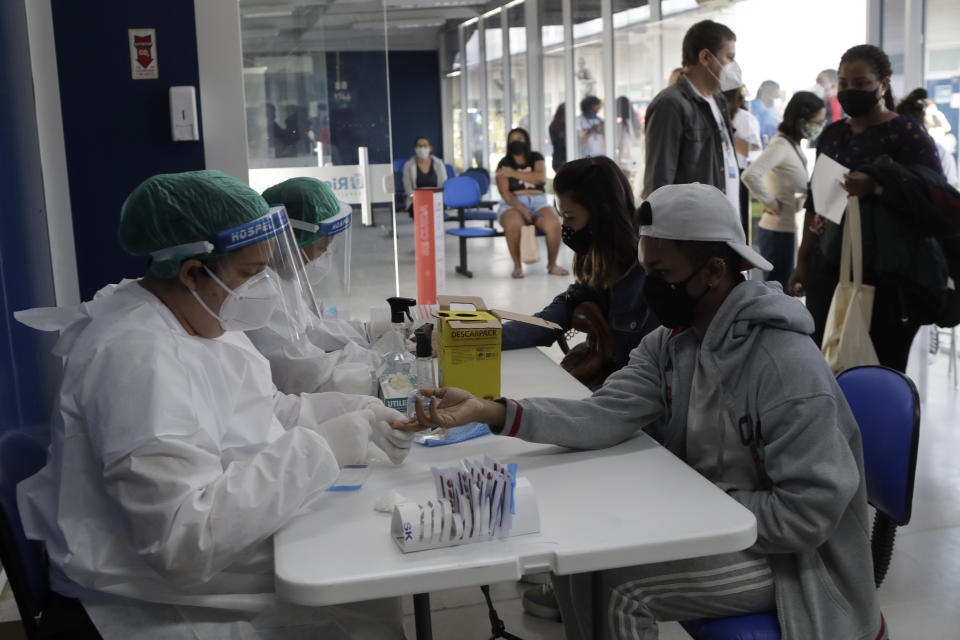 A health worker gives a resident a COVID-19 test on the first day of a three-day vaccination campaign for people over age 35 in the Complexo da Maré favela of Rio de Janeiro, Brazil, Thursday, July 29, 2021. Some recipients will be monitored to study the rate of protection the vaccines provide and the extent to which virus variants are circulating. (AP Photo/Bruna Prado)