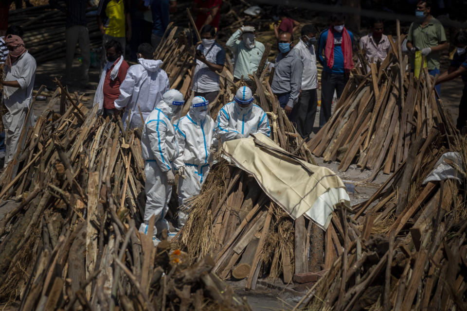 People perform rituals next to a funeral pyre for a family member who died of COVID-19 at a ground that has been converted into a crematorium for mass cremation of COVID-19 victims in New Delhi, India, Saturday, April 24, 2021. Delhi has been cremating so many bodies of coronavirus victims that authorities are getting requests to start cutting down trees in city parks, as a second record surge has brought India's tattered healthcare system to its knees. (AP Photo/Altaf Qadri)