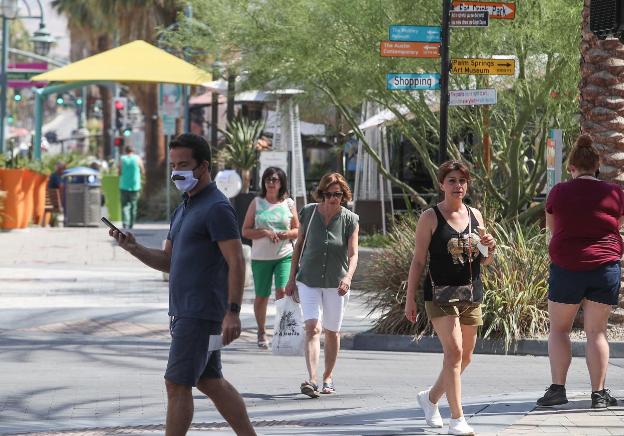 People walk around downtown Palm Springs with and without masks after the state said people who are vaccinated no longer need to wear masks, June 15, 2021.