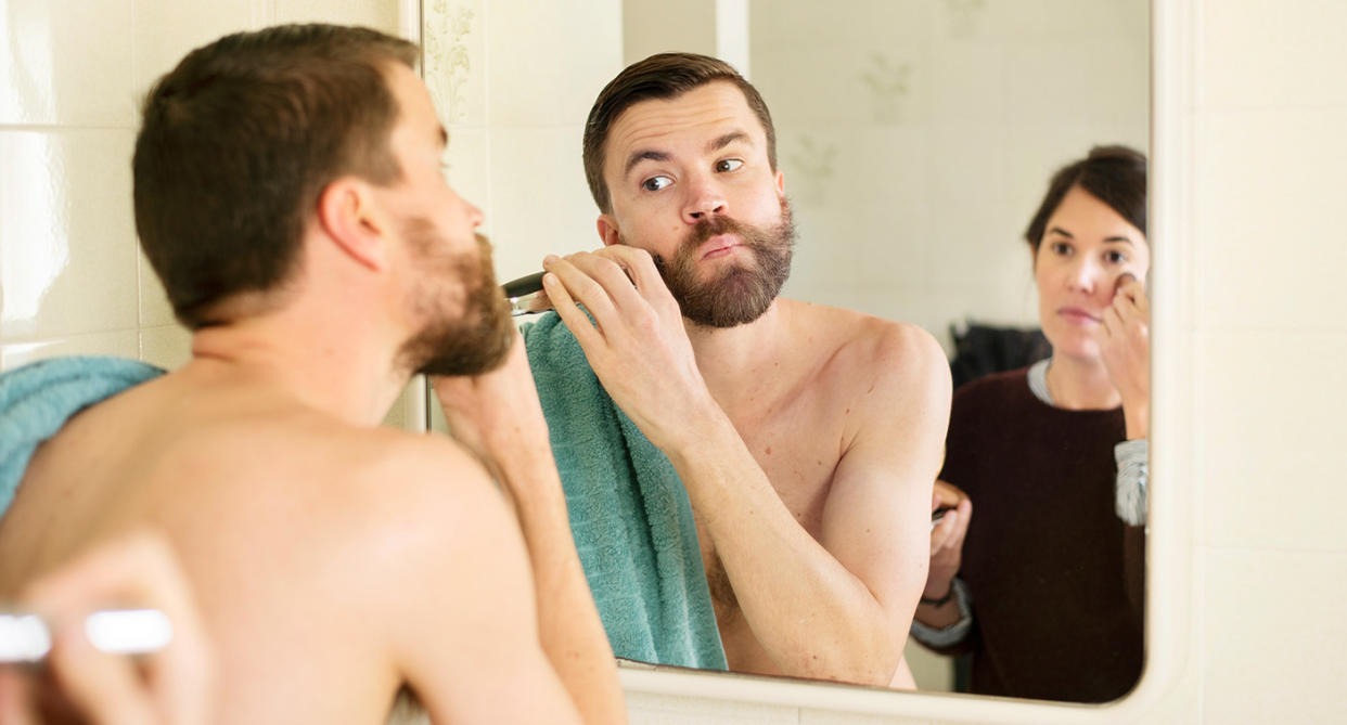 Couple in bathroom in mirror, one holding a towel to represent sharing with a partner. (Getty Images)