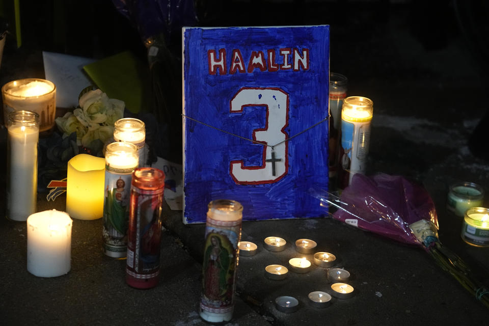A painting that shows the number of Buffalo Bills' Damar Hamlin is illuminated by candles during a prayer vigil outside University of Cincinnati Medical Center, Tuesday, Jan. 3, 2023, in Cincinnati. Hamlin was taken to the hospital after collapsing on the field during an NFL football game against the Cincinnati Bengals on Monday night. (AP Photo/Darron Cummings)