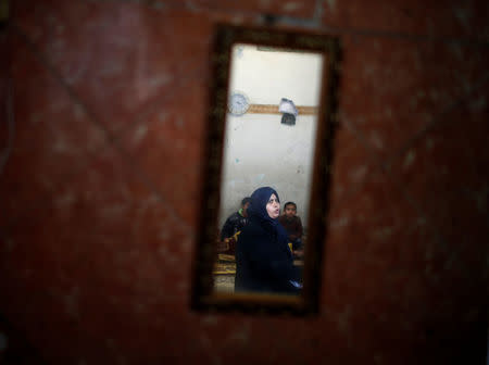 A Palestinian woman is reflected in a mirror as she sits in her house in Al-Shati refugee camp in Gaza City January 17, 2018. REUTERS/Mohammed Salem