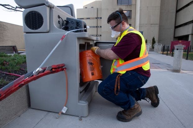 Student Patrick D'Aoust places a wastewater collection container inside a pump station on the University of Ottawa campus on Thursday, April 8, 2021.