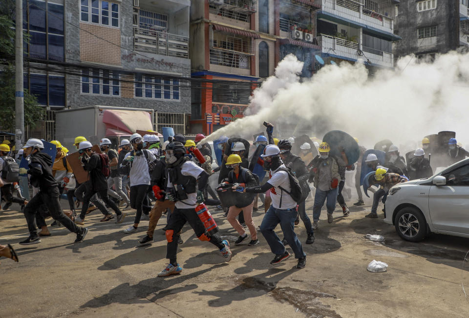 FILE - Anti-coup protesters run as one of them discharges a fire extinguisher to counter the impact of tear gas fired by riot policemen in Yangon, Myanmar, Wednesday, March 3, 2021. As Feb. 1, 2023, marks two years after Myanmar’s generals ousted Aung San Suu Kyi’s elected government, thousands of people have died in civil conflict and many more have been forced from their homes in a dire humanitarian crisis. (AP Photo, File)