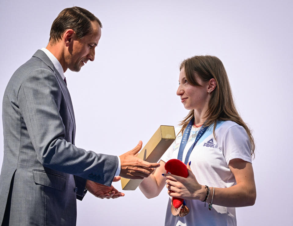 Gimnasta română Ana Maria Barbusu primește o medalie olimpică de bronz de la Mihai Covaliu (L), președintele Comitetului Olimpic Român (COSR), pe 16 august 2024 la București, România, după ce o gimnastă din Statele Unite a fost deposedată de medalie. Barbuso a primit medalia olimpică de bronz la exerciții la sol, care a fost acordată inițial lui Jordan Chiles, în urma unei decizii a Comitetului Olimpic Internațional (CIO). Decizia CIO a urmat o hotărâre a Curții de Arbitraj pentru Sport (CAS) care a anulat reevaluarea scorului lui Chiles pe motiv că contestația scorului său de dificultate a fost depusă de echipa SUA la patru secunde după termenul de reglementare, stabilit la unu. minut. (Foto: Daniel Mihăilescu/AFP) (Foto: Daniel Mihăilescu/AFP via Getty Images)