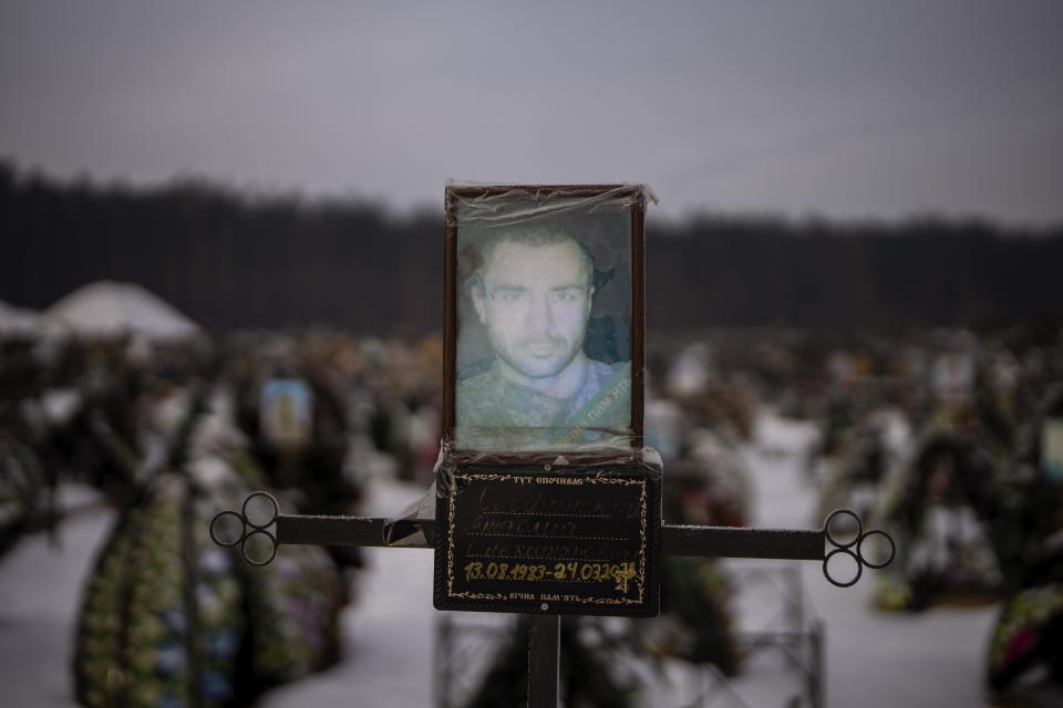 A faded portrait of Anatoly Olofunskyi, 39, sits on his grave at a cemetery in Irpin, Ukraine, on the outskirts of Kyiv, on Friday, Feb. 10, 2023. Another portrait of Anatoly sits in his mother's bedroom. Ludmilla starts her day by saying "Good morning, son." At night he appears in her dreams and tells her not to cry. (AP Photo/Emilio Morenatti)