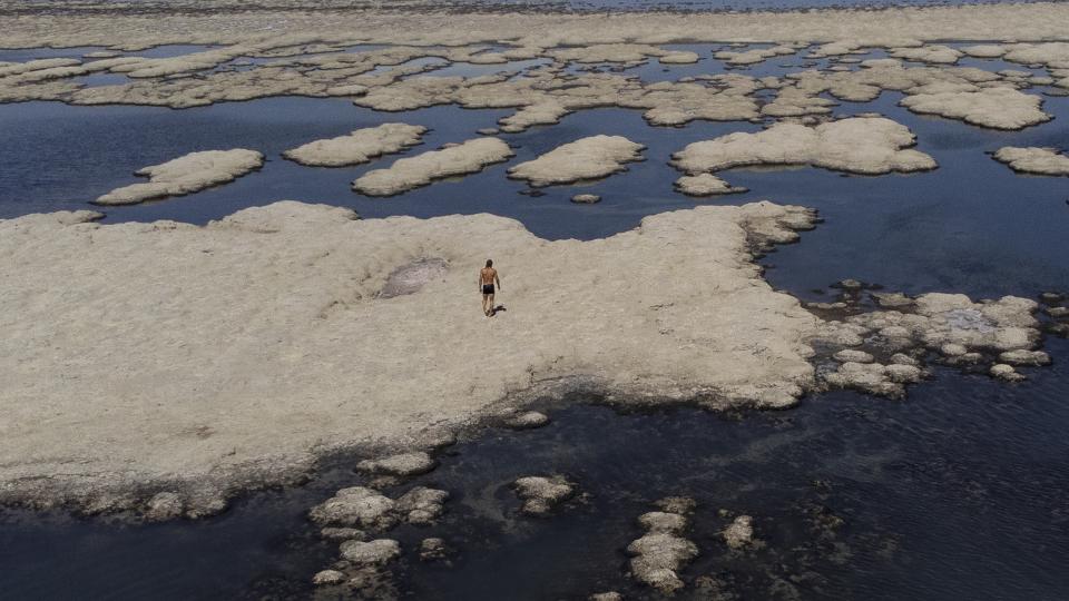 FILE - Olof Wood walks across reef-like structures called microbialites, exposed by receding waters at the Great Salt Lake, Sept. 6, 2022, near Salt Lake City. After years of sailboats being hoisted out of the shrinking Great Salt Lake amid fears they might not return, sailors are back this summer. (AP Photo/Rick Bowmer)