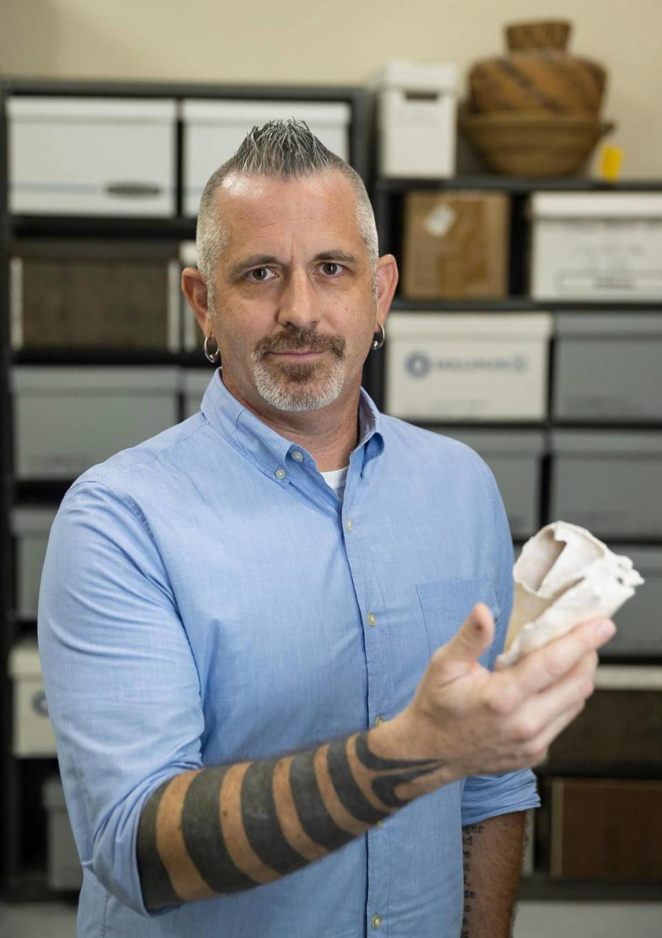 William Pestle, an archaeologist and chairman of anthropology at the University of Miami, is photographed inside the his department’s artifact storage room holding a conch shell from a prehistoric archaeological site in the Florida Keys.