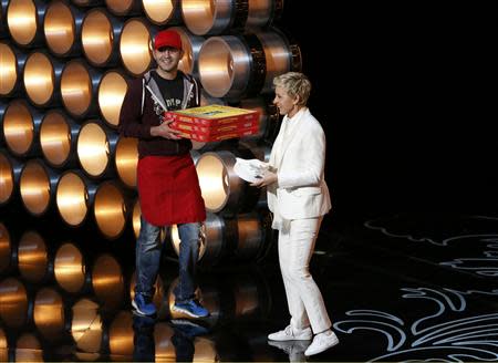 Show host Ellen DeGeneres receives pizza to be given to the audience at the 86th Academy Awards in Hollywood, California March 2, 2014. REUTERS/Lucy Nicholson