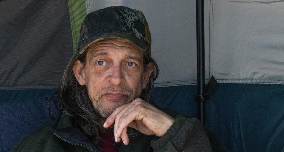 Jeff Augustino, 62, sits outside his tent in the Toms River homeless camp. Augustino can't work because he has ruptured discs in his back that he couldn't have repaired because he was already being treated for cancer.