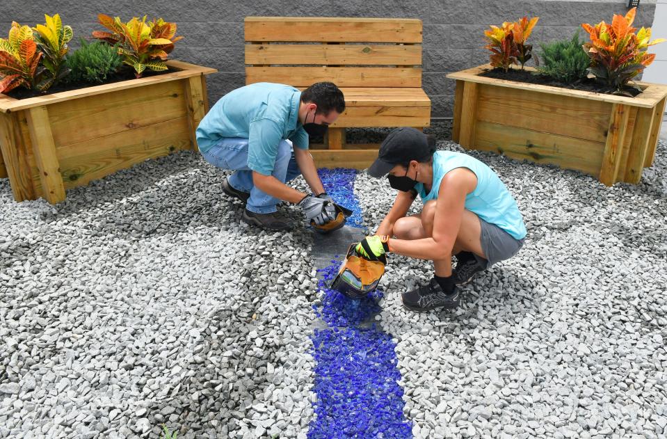 Christina Navedo and son Brandon place blue rocks at the memorial garden created in memory of West Melbourne Police Capt. Carlos Navedo, who was her husband and his father. The captain died unexpectedly on June 4, 2022. Dozens of volunteers, spearheaded by members of the West Melbourne Home Depot, along with several members of the City Council, Police Department and others, made this memorial garden at the police station.