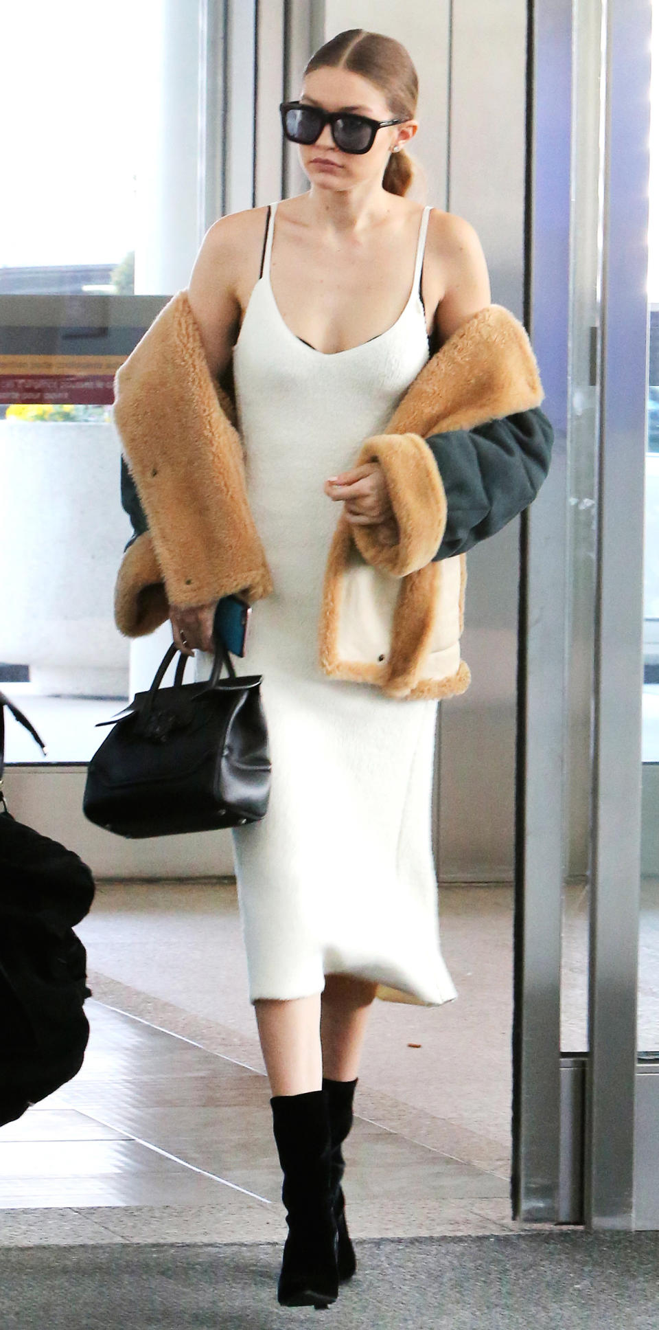 <p>The model walked across Toronto's Pearson International Airport in a sexy slip dress with an off-the-shoulder, fur-lined coat. </p>