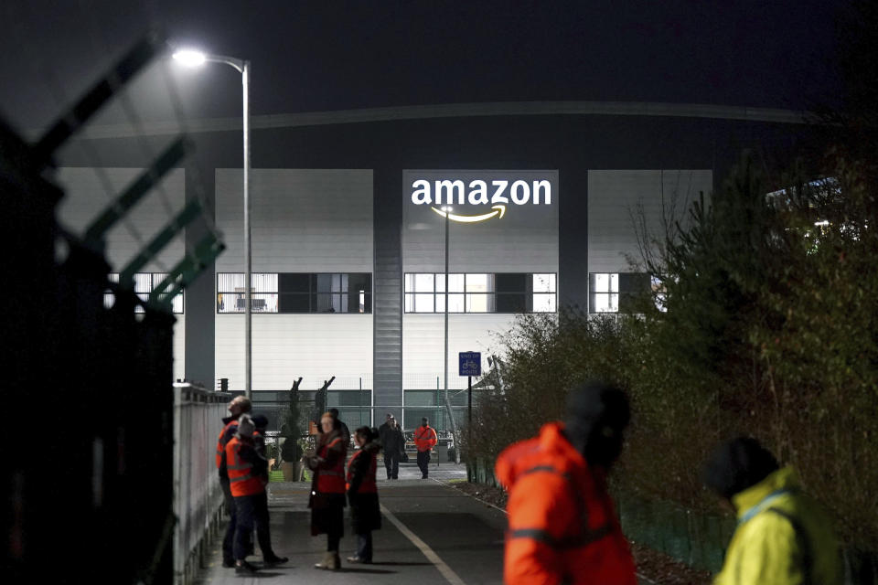 Members of the Amazon security keep an eye on members of the GMB union picketing outside the Amazon fulfilment centre as Amazon workers stage their first ever strike in the UK in a dispute over pay, in Coventry, England, Wednesday, Jan. 25, 2023. (Jacob King/PA via AP)
