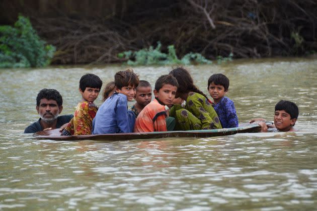 A man (L) along with a youth use a satellite dish to move children across a flooded area after heavy monsoon rainfalls in Jaffarabad district, Balochistan province, on Aug. 26, 2022. Heavy rain continued to pound parts of Pakistan on August 26 after the government declared an emergency to deal with monsoon flooding it said had 