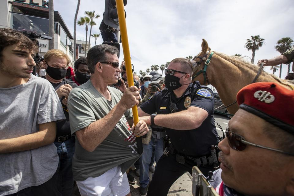 A Huntington Beach police officer arrests a man carrying a Gadsden flag at Sunday's dual rallies