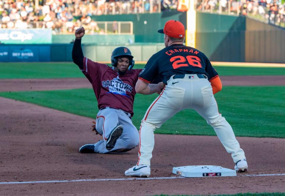 Sacramento River Cats’ Yusniel Díaz slides safely into third base, guarded by San Francisco Giants’ Matt Chapman, during an exhibition game Sunday.