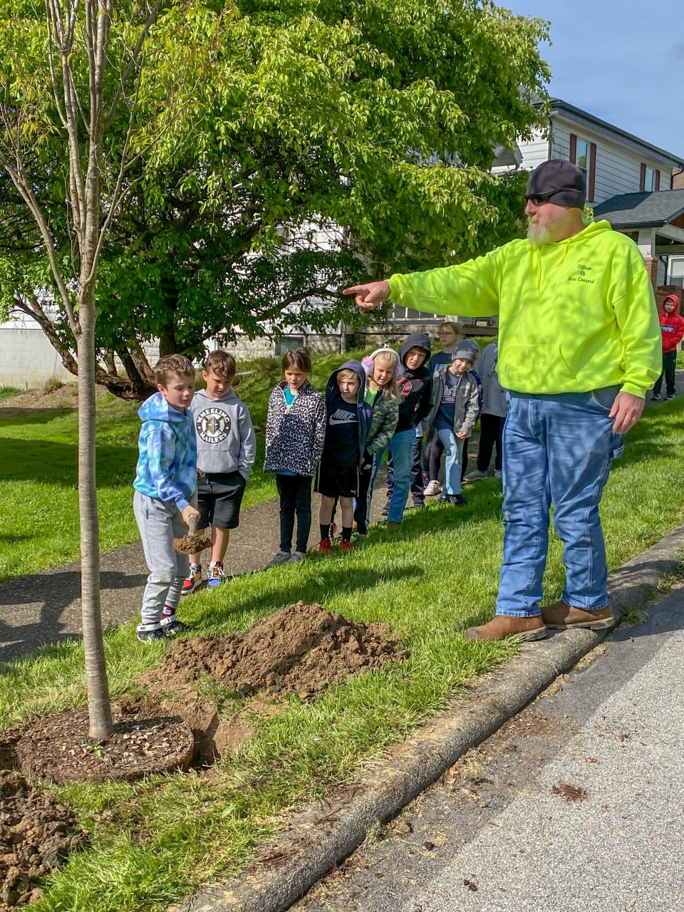 Village Operations Manager Trent Johnson (right) directs students on how to pitch in with the Arbor Day tree planting.