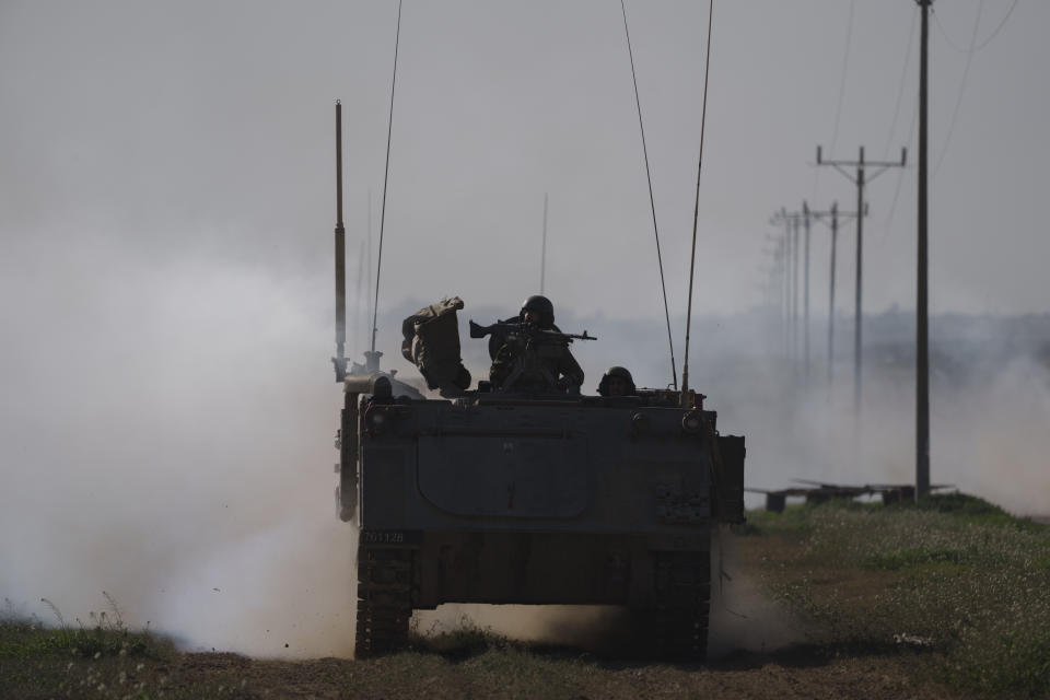 Israeli soldiers travel on an army armored personnel carrier (APC) near the Israeli-Gaza border as smoke rises to the sky in the Gaza Strip, seen from southern Israel, Sunday, Jan. 21, 2024. (AP Photo/Leo Correa)