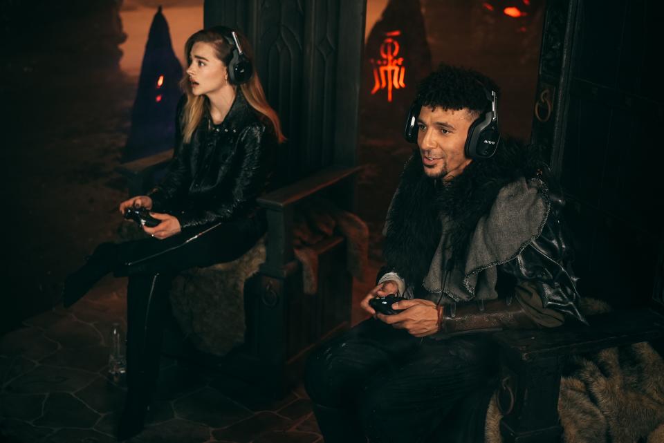 Chloe Grace Moretz and Khleo Thomas with headsets on holding video game controllers.