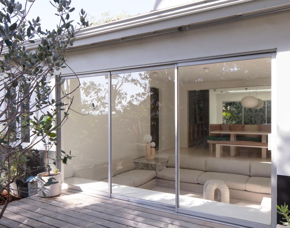 Original glass sliding doors fuse the leafy patio with the concave living room.