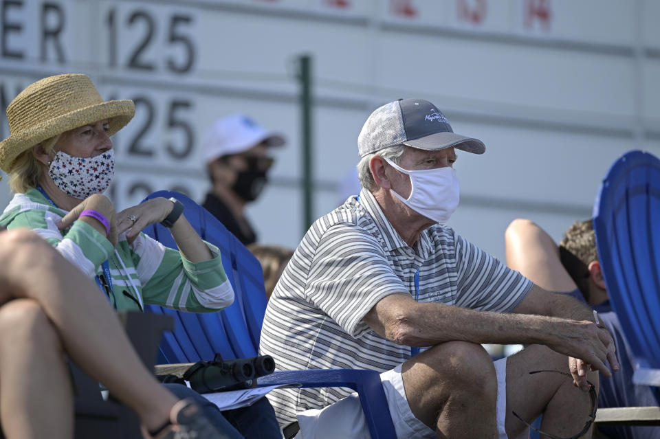 Spectators wear masks while watching along the 18th green during the final round of the Tournament of Champions LPGA golf tournament, Sunday, Jan. 24, 2021, in Lake Buena Vista, Fla. (AP Photo/Phelan M. Ebenhack)