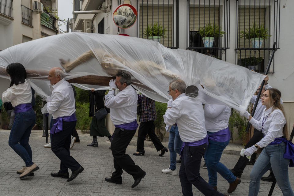 Members of the "Vera Cruz" Catholic brotherhood carry a figure of Jesus Christ, covered with a plastic sheet to protect it from the rain, during a Holy Week procession in the southern town of Quesada, Spain, Friday, March 29, 2024. (AP Photo/Bernat Armangue)