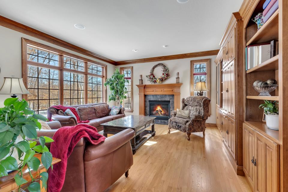 A gas fireplace and wood mantle provide ambiance in the family room as does the wall of built-in bookcases. The bookcase wall features doors for hiding entertainment and providing a sleek look in the space when not in use.