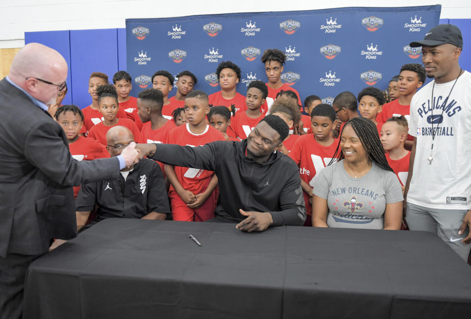 New Orleans Pelicans forward Zion Williamson shakes hands with New Orleans Pelicans vice president of basketball operations David Griffin after signing his contract extension surrounded by his family and children attending camp at the Dryades YMCA in New Orleans, Wednesday, July 6, 2022. (Max Becherer/The Times-Picayune/The New Orleans Advocate via AP)