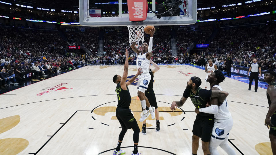 Memphis Grizzlies guard Ja Morant (12) goes to the basket against New Orleans Pelicans guard CJ McCollum (3) in the second half of an NBA basketball game in New Orleans, Tuesday, Dec. 19, 2023. The Grizzlies won 115-113. (AP Photo/Gerald Herbert)