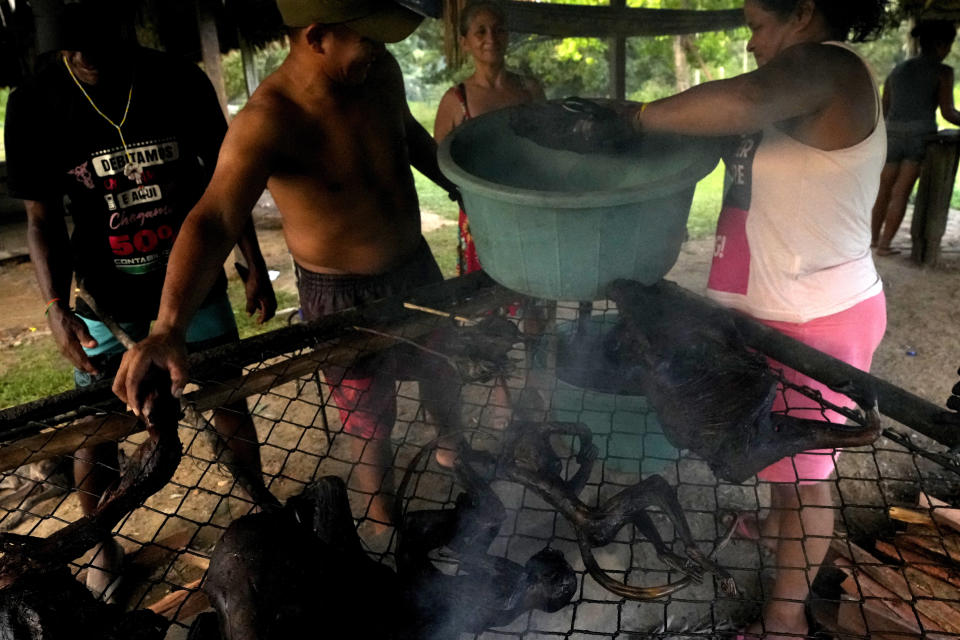 Miembros de la comunidad sacan la carne de una parrilla para preparar Moqueada, una comida tradicional de los tembé elaborada con carne de caza, durante el rito de madurez Wyra'whaw, en el centro ritual Ramada, en la aldea Tenetehar Wa Tembe, en la tierra indígena Alto Río Guamá, en el estado de Pará, Brasil, el 9 de junio de 2023. (AP Foto/Eraldo Peres)