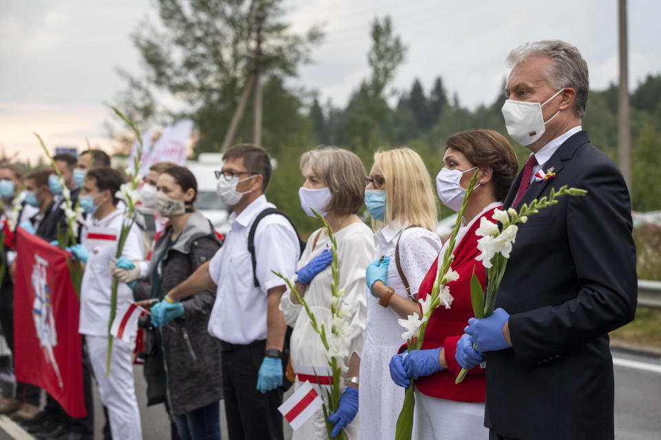 Lithuania's President Gitanas Nauseda, right, and his wife Diana Nausediene, second from right, and other supporters of Belarus opposition participate in a "Freedom Way", a human chain of about 50,000 strong from Vilnius to the Belarusian border, during a protest near Medininkai, Lithuanian-Belarusian border crossing east of Vilnius, Lithuania, Sunday, Aug. 23, 2020. In Aug. 23, 1989, around 2 million Lithuanians, Latvians, and Estonians joined forces in a living 600 km (375 mile) long human chain Baltic Way, thus demonstrating their desire to be free. Now, Lithuania is expressing solidarity with the people of Belarus, who are fighting for freedom today. (AP Photo/Mindaugas Kulbis)