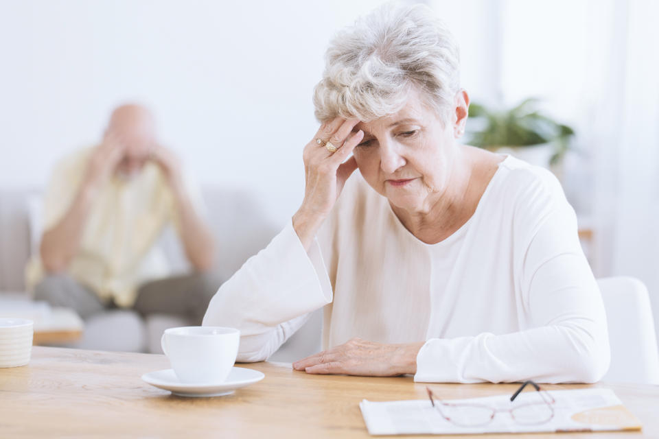 Sad senior woman sitting at table after a quarrel with her husband